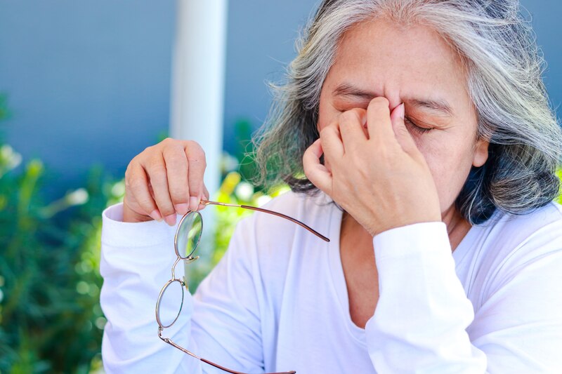 woman with eyes in pain holding her glasses